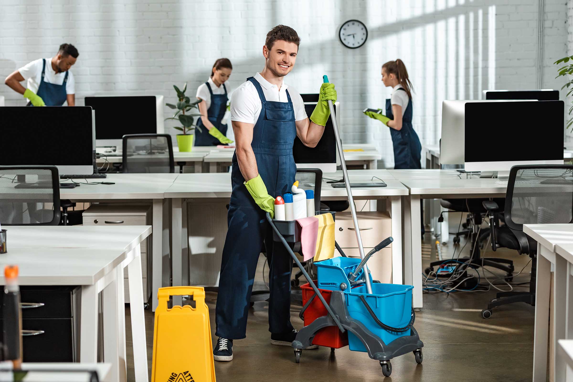 Commercial cleaner moving a janitorial cart with cleaning supplies in a workplace
