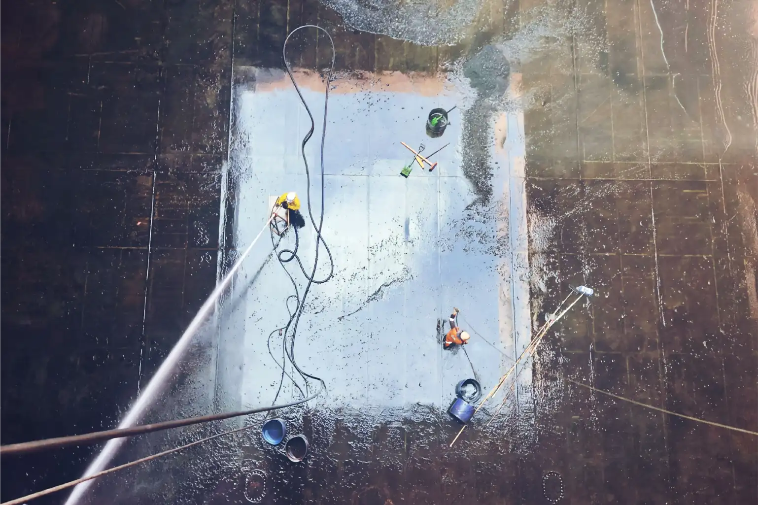 Aerial drone view of commercial pressure washing on a muddy outdoor floor in Huntsville, AL