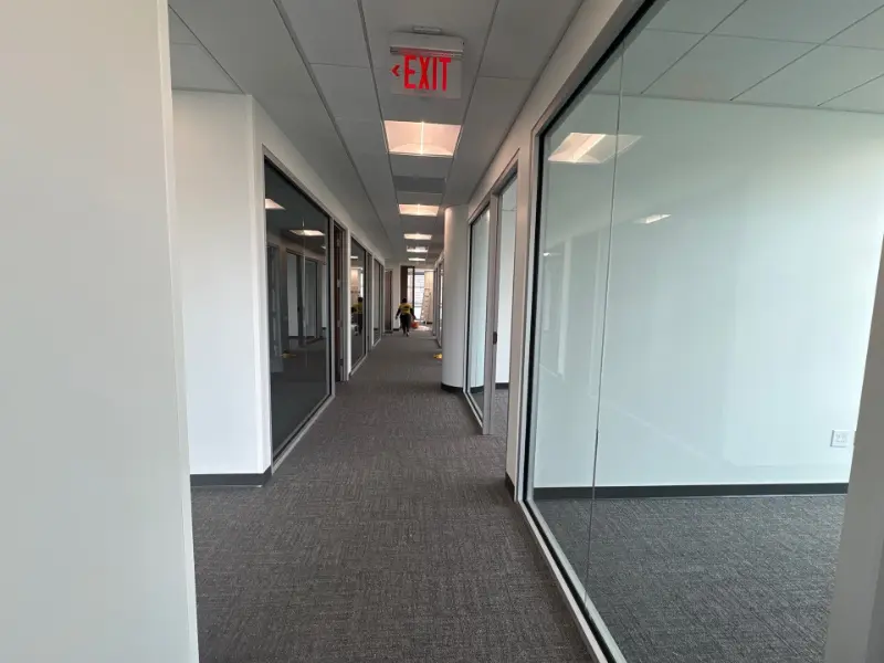 Hallway of glassed conference rooms with carpeted floor disinfected by Mid City Commercial Cleaning in Huntsville, AL