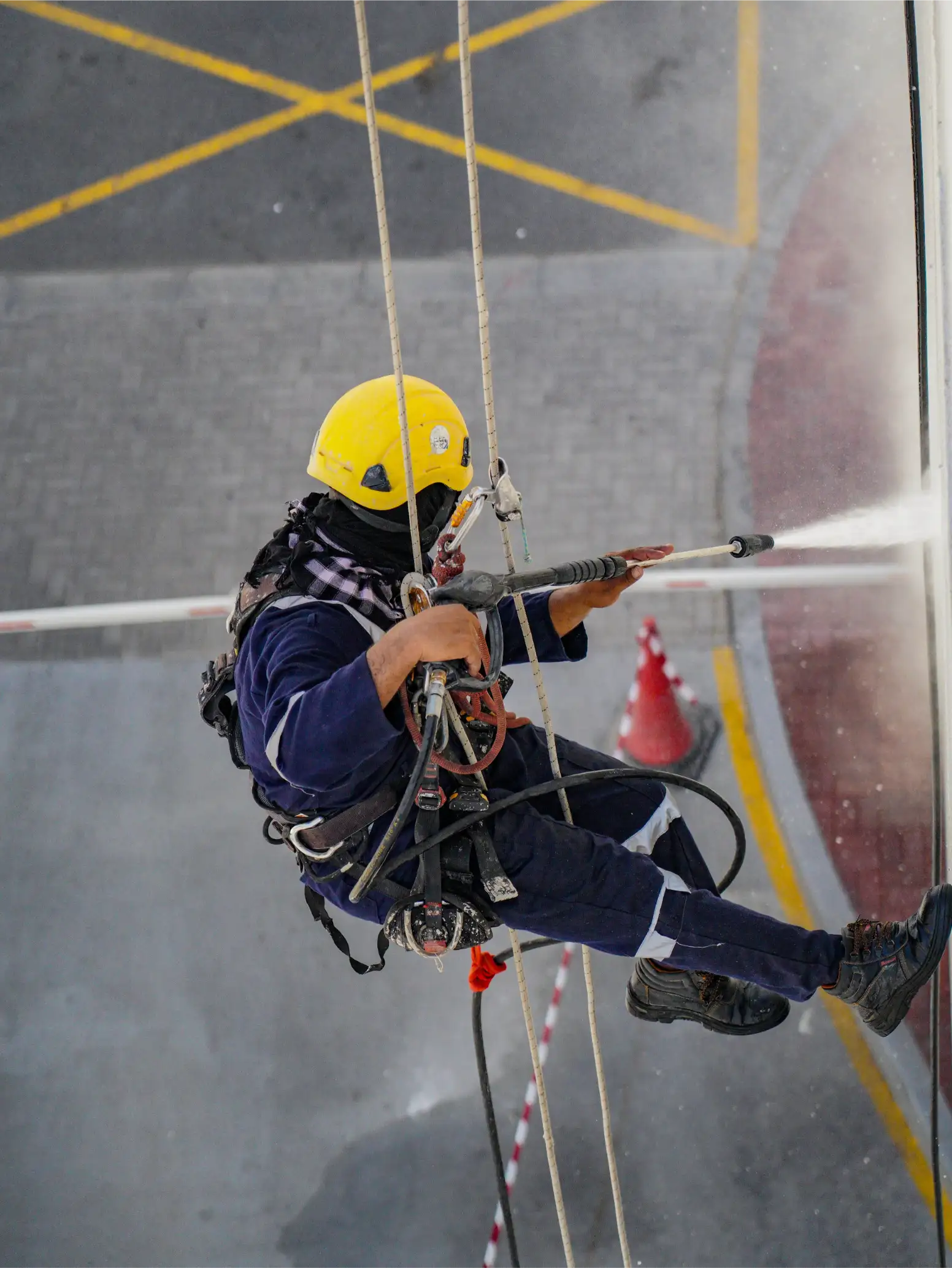 Technician on a harness pressure washing a commercial building exterior in Huntsville, AL
